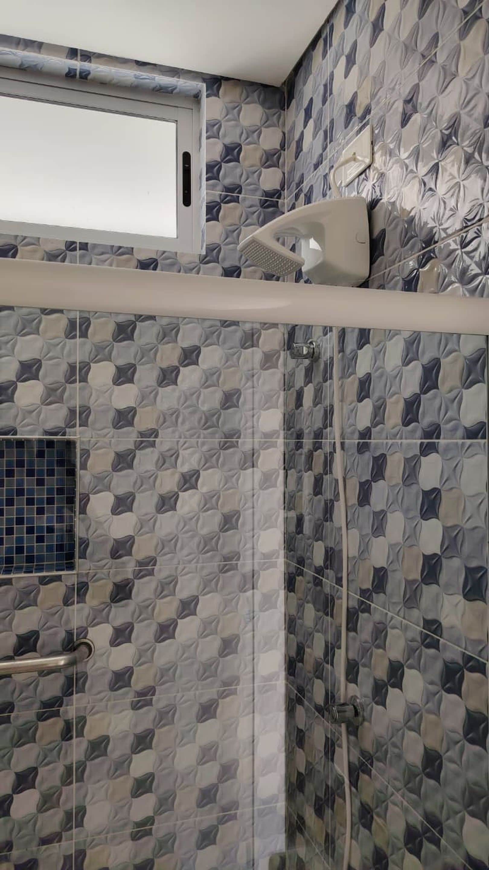 Ein Duschbereich mit einer wandgestalteten Fliesenwand, einem Fenster über der Dusche und einem Wand-Händetrockner.