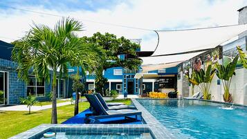 A swimming pool with lounge chairs, palm trees, and a building with blue tiles.