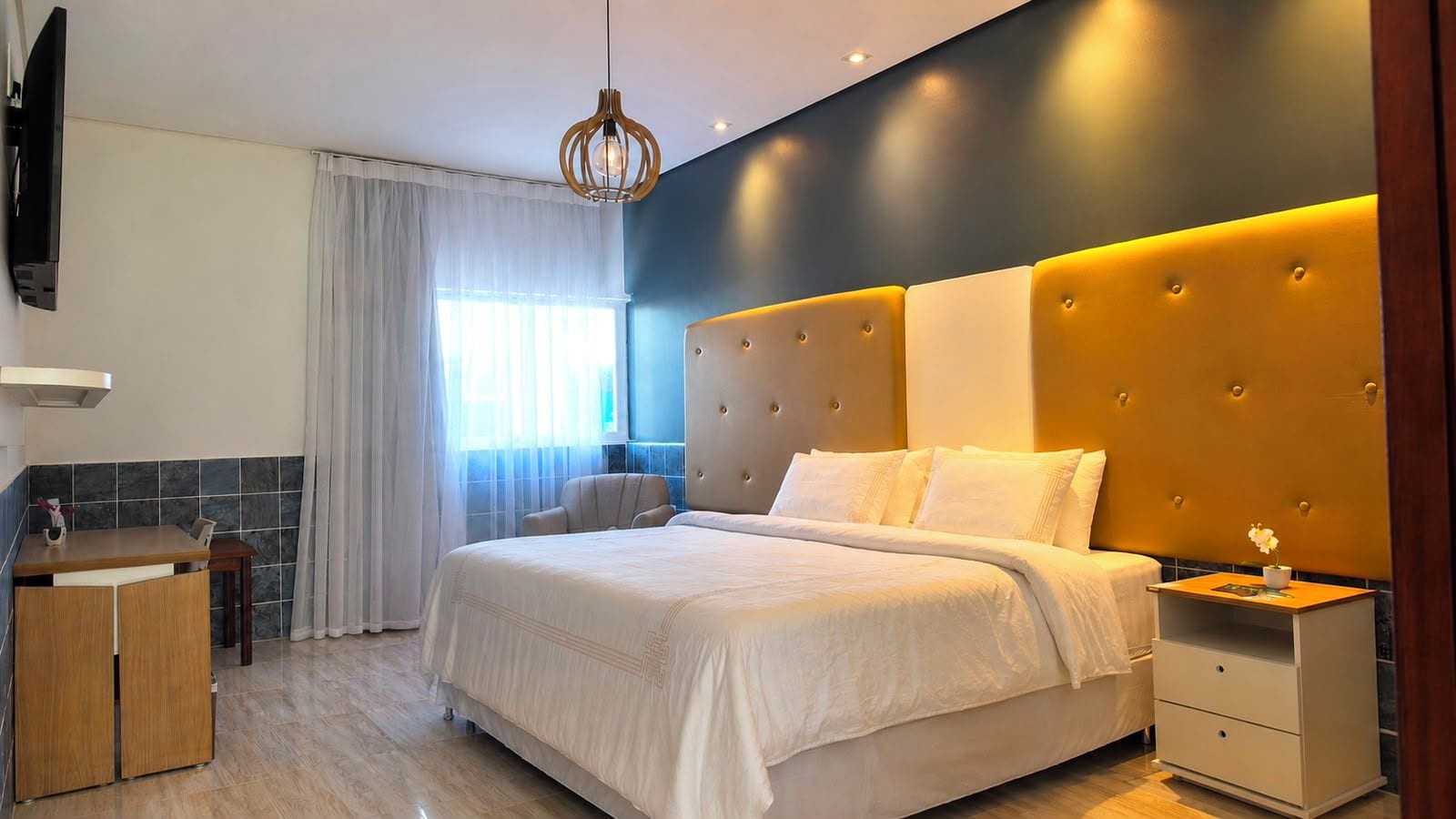 Una habitación de hotel moderna con una cama grande, una mesita de noche, un escritorio pequeño y una silla.