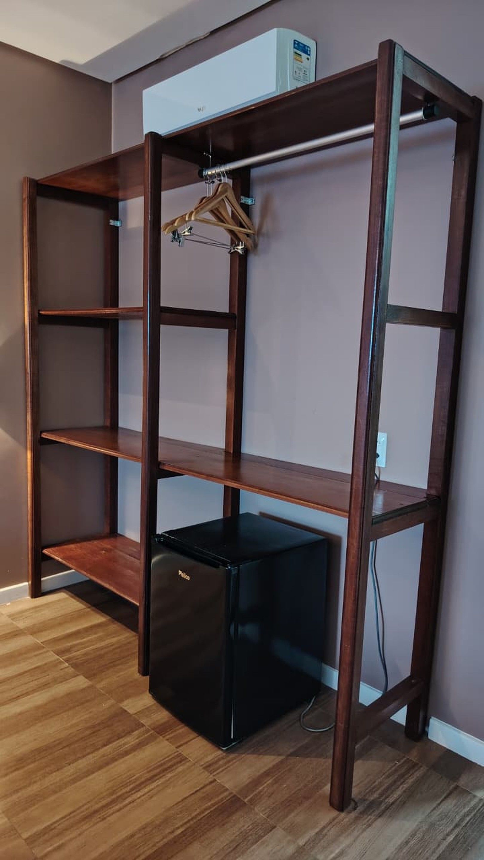 Una habitación con una estantería de madera empotrada, un refrigerador negro y un perchero.