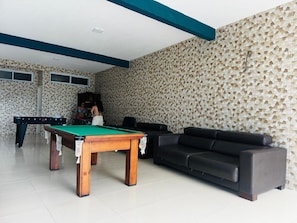 A room with a pool table, a sofa, and a wall with a geometric pattern.
