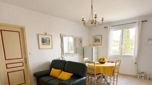 Ein Wohnzimmer mit einer Couch, einem Esstisch, Stühlen, einer Kandelaber und einem Kühlschrank.