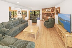 A living room with a sofa set, a coffee table, and a television on a wooden stand. - 1 Mile Away From Snow Summit! PET FRIENDLY! Game Room W/ Pool + Ping Pong Combo Table & Foosball! Fenced Back Yard! Deck W/ Patio Furniture & Propane BBQ! (Big Bear Lake)