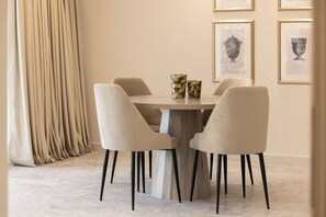 A dining area with a round table, six chairs, and two vases. - Thirty Five Westbay Luxury Apartments (Doha)