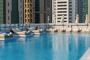 A rooftop pool with lounge chairs and umbrellas, surrounded by high-rise buildings. - Thirty Five Westbay Luxury Apartments (Doha)