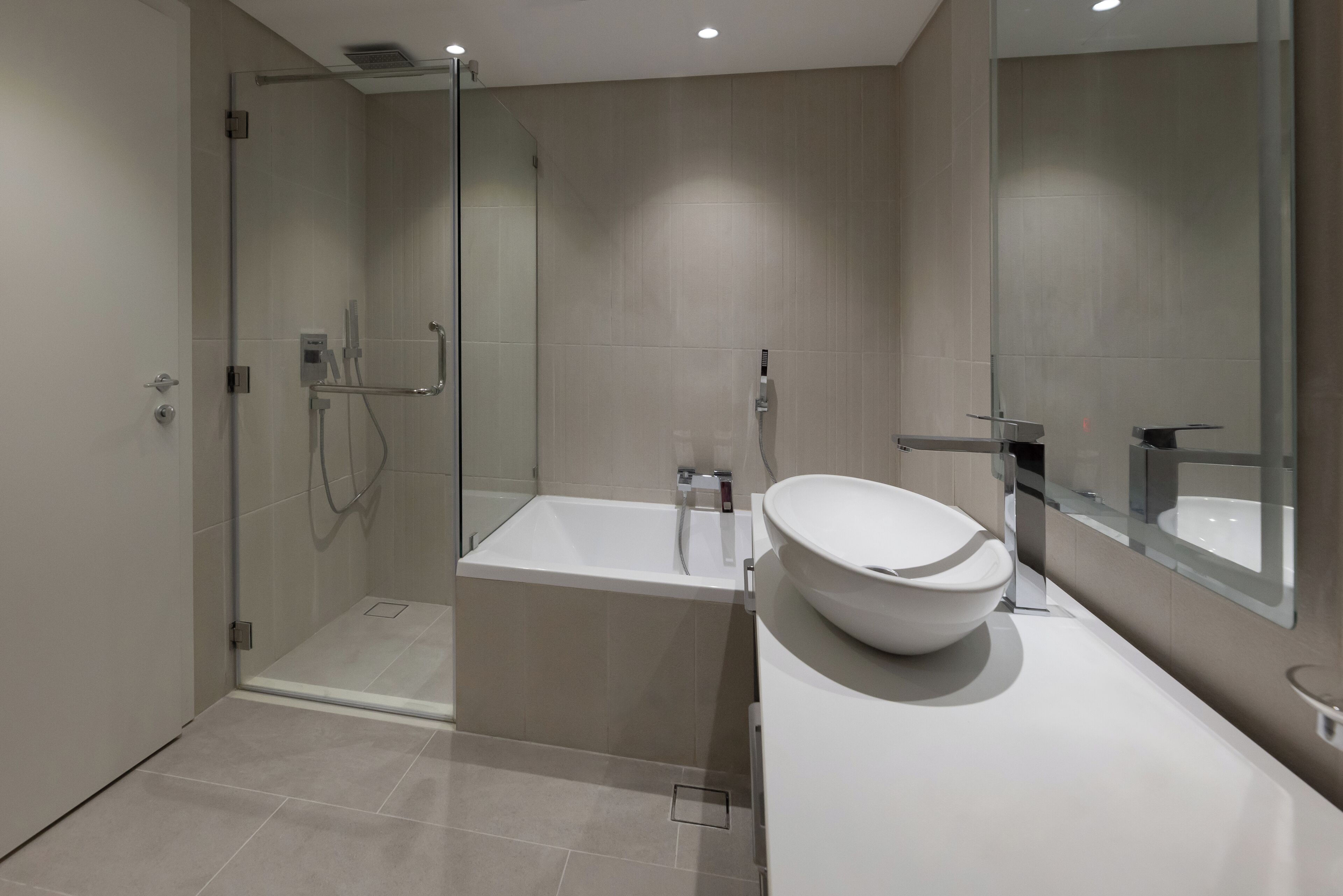 Un baño moderno con cabina de ducha de vidrio, una bañera independiente y un espejo grande.