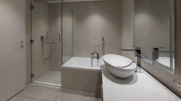 Un baño moderno con cabina de ducha de vidrio, una bañera independiente y un espejo grande.