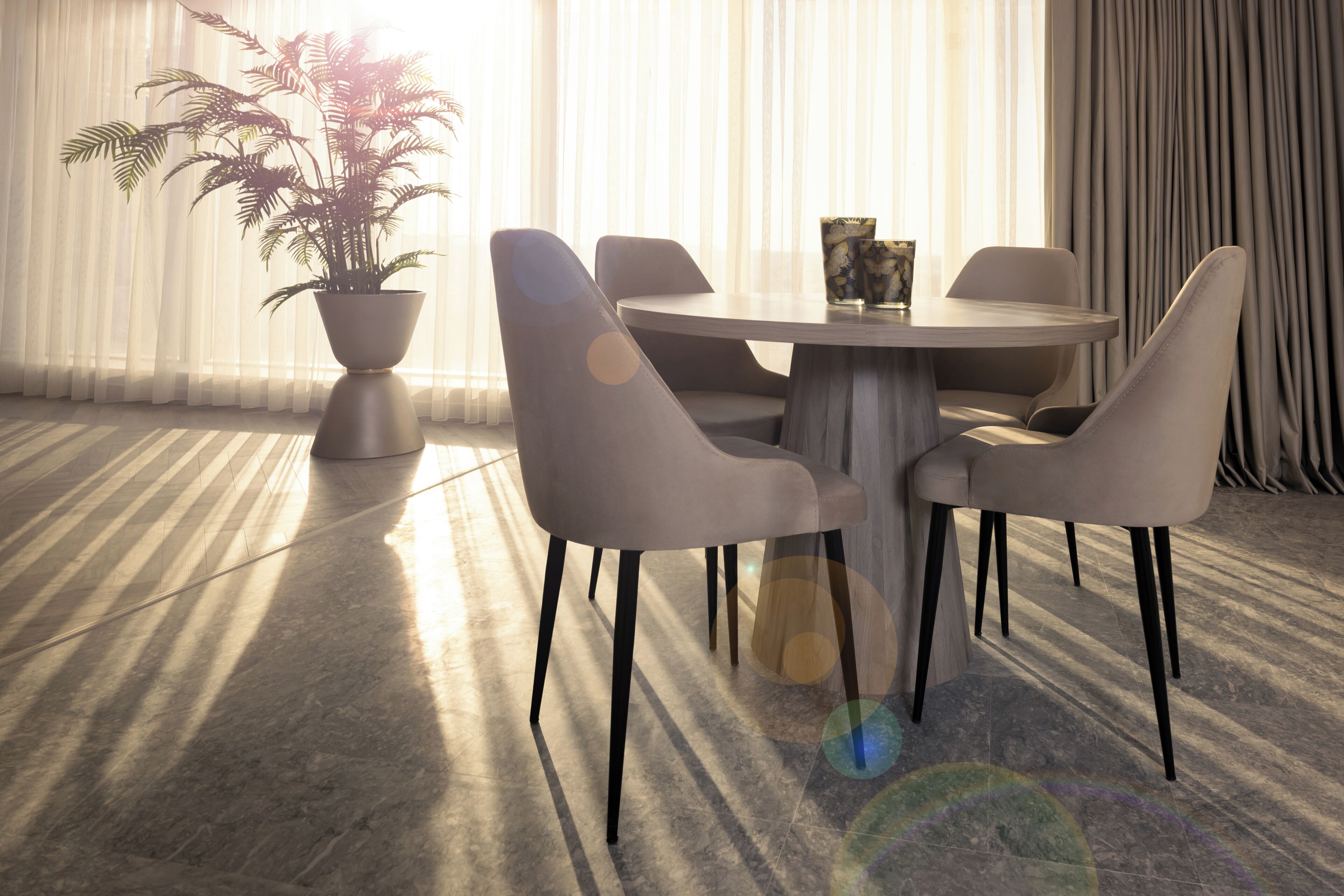 Un espace repas moderne avec une table ronde, quatre chaises, une plante en pot et un vase.