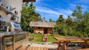 Una terraza de madera con una parrilla y zona de estar al aire libre.