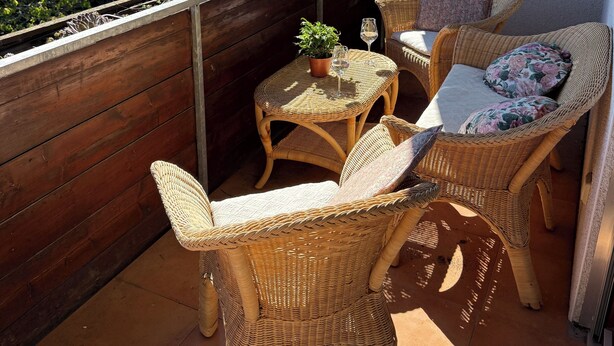 A balcony with wicker furniture, a small table, and a potted plant. - Beautiful garden apartment with a view of the Hegau countryside. (Singen (Hohentwiel))