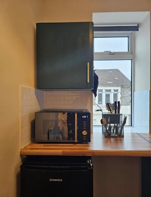 Eine Küche mit Mikrowelle, Toaster und einem schwarzen Gerät mit der Aufschrift 'SUBCOLD' auf der Arbeitsfläche.
