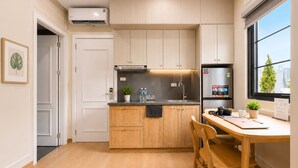 Una cocina moderna con armarios de madera, un refrigerador de acero inoxidable, un fregadero y un comedor con mesa y sillas.