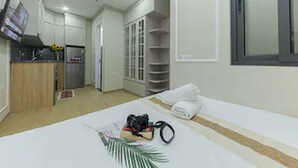 Una habitación pequeña con cama, kitchenette, armario y ventana.