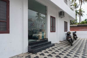 A building with a glass entrance, steps leading up to it, and a tiled floor.
