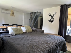 Une chambre moderne comprenant un lit, une table à manger, des chaises, un escalier et une décoration murale représentant une tête de cerf.