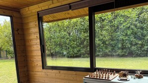 Una habitación con paredes de madera, un ventanal grande, un tablero de ajedrez y una puerta.