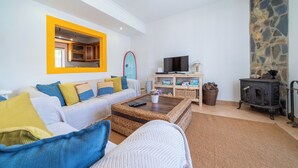 Ein Wohnzimmer mit einer Couch, Couchtisch, Fernseher und einer Steinwand.