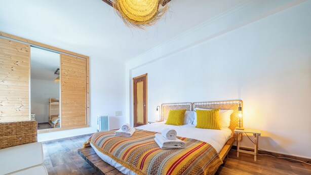 Ein Schlafzimmer mit einem großen Bett, Holzboden, einem Holzschrank und einem Spiegel.