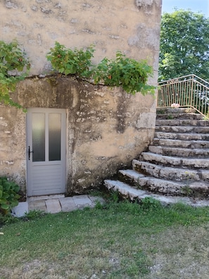 A building with a white door, stone steps, and a metal railing.