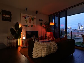 Ein modernes Wohnzimmer mit einem großen Fenster, einer Weltkarte an der Wand und einem gemütlichen Sofa.