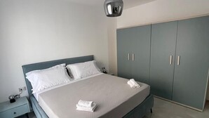 A bedroom with a bed, a nightstand, a wardrobe, and a pendant light. - Gheloi Apartments (Gela)