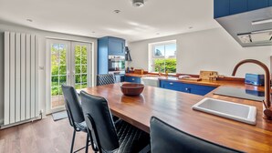 Cozinha moderna com ilha central, eletrodomésticos embutidos e vista para o verde lá fora.