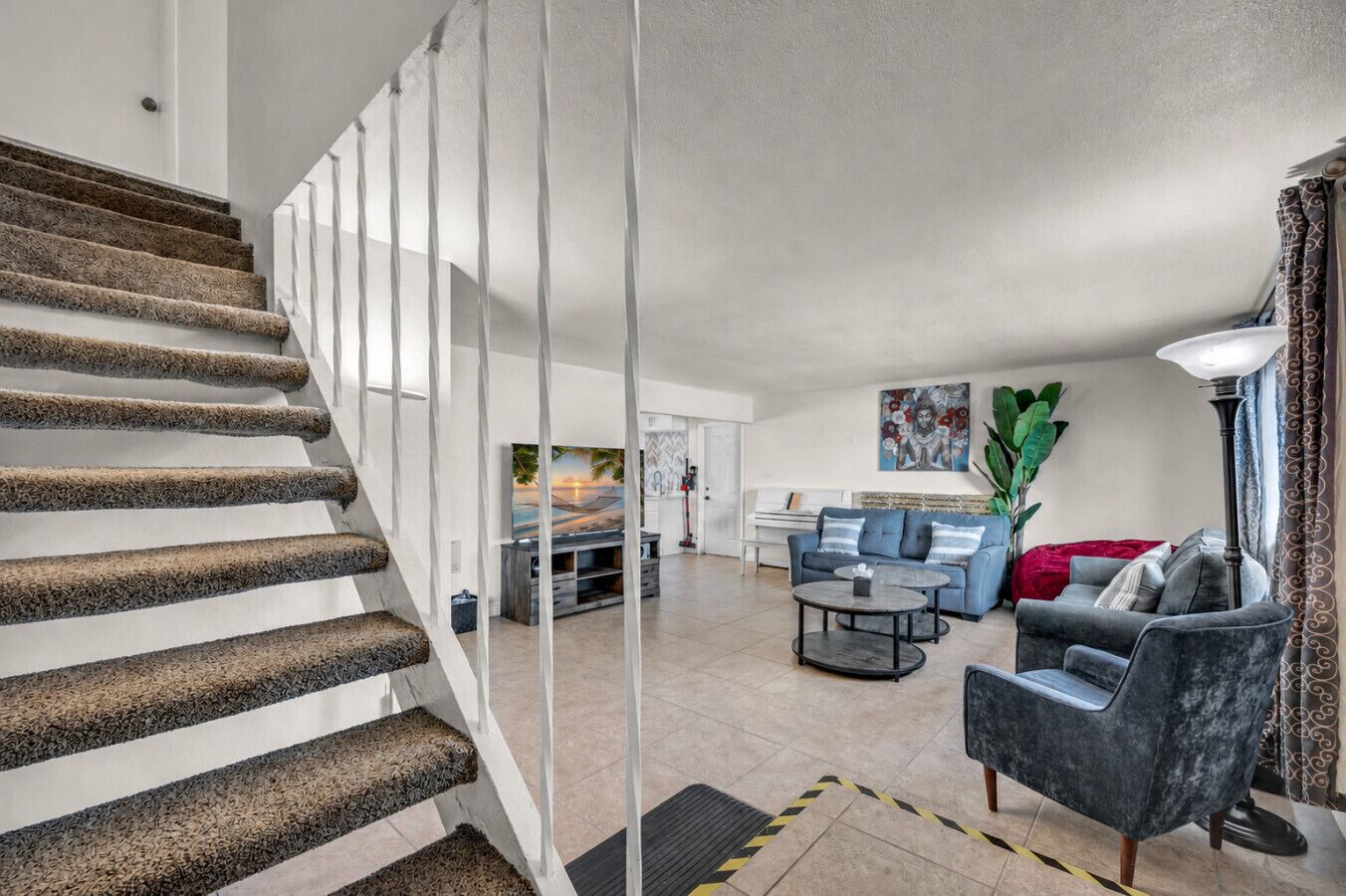 A staircase with a textured carpet, a living room with a sofa, a coffee table, and a television.