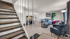 A staircase with a textured carpet, a living room with a sofa, a coffee table, and a television. - 7BR Vegas Oasis • Big Pool • Games • Near Strip (Las Vegas)