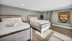 A modern hotel room with two beds, a wooden floor, a Buddha painting, and recessed ceiling lights. - 7BR Vegas Oasis • Big Pool • Games • Near Strip (Las Vegas)