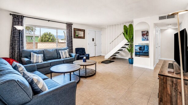A spacious living area with a sofa set, coffee table, and a staircase leading to another level. - 7BR Vegas Oasis • Big Pool • Games • Near Strip (Las Vegas)
