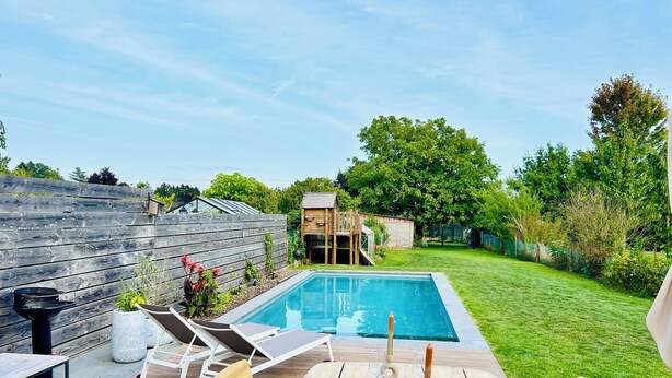 Un giardino sul retro con piscina, un pontile in legno e un'area pranzo con sedie e tavoli.
