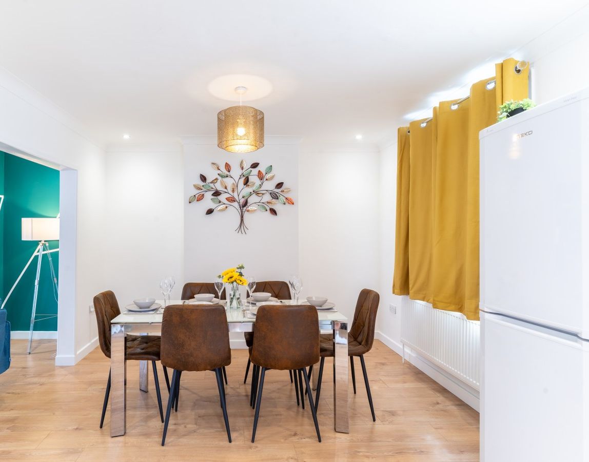 Dining table opens through to the lounge with the blue sofa.
