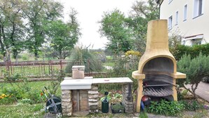 Zona cuina exterior amb un banc de pedra, una barbacoa i un forn de pedra.