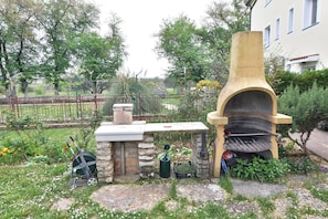 An outdoor kitchen area with a stone bench, a grill, and a stone oven. - Cozy and practical studio in Šćavonija (Murine)