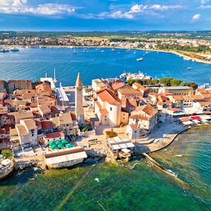 An aerial view of a coastal town with historic buildings, a prominent church tower, and a marina with boats. - Cozy and practical studio in Šćavonija (Murine)