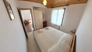 A bedroom with a bed, a wooden ceiling, a window with curtains, and a door leading to a bathroom. - Peaceful apartment near Umag (Murine)