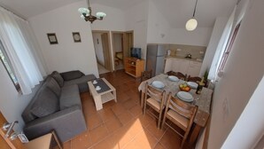A compact living space with a sofa, dining table, chairs, and a kitchenette. - Peaceful apartment near Umag (Murine)