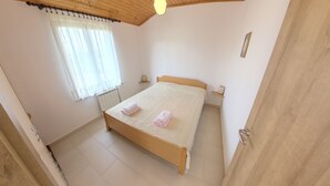 A bedroom with a wooden bed, a radiator, a window with curtains, and a door. - Peaceful apartment near Umag (Murine)