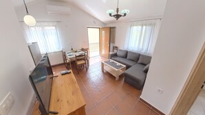 A living room with a sofa, a coffee table, and a TV. There is a dining area with a table and chairs. - Peaceful apartment near Umag (Murine)