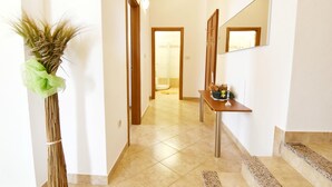 A hallway with a staircase, a mirror, and a table with a vase. - Bright flat with shared pool in Tar (Tar)