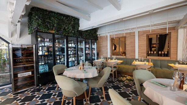 A restaurant with a modern interior, featuring a bar area with glassware, a seating area with tables and chairs, and a patterned floor. - Barrique Livezii 3 (Brașov)