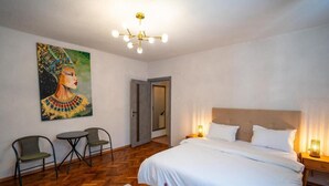 A bedroom with a bed, bedside tables, a painting, and a chandelier. - Barrique Livezii 3 (Brașov)