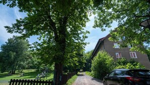 A gravel path leading to a building with a sloped roof, surrounded by greenery and a parked car. - Barrique Livezii 3 (Brașov)