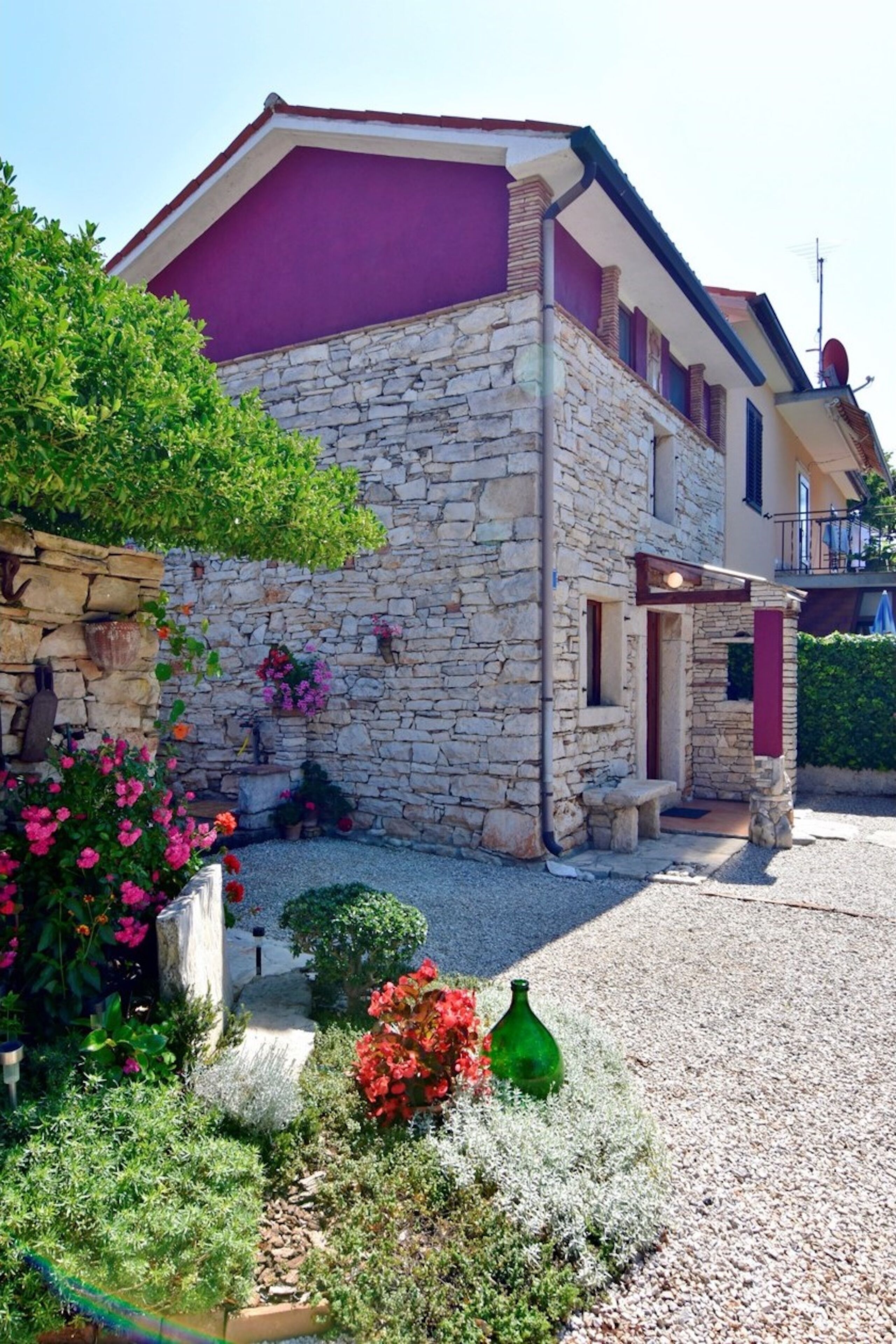 A stone building with a purple facade, a stone staircase, and a gravel driveway.