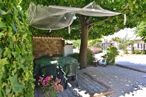 A covered outdoor seating area with a table and chairs, surrounded by greenery and a patterned wall. - Stone house only 150m from the sea (Zambratija)