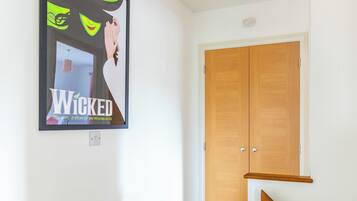Une pièce avec une porte en bois, une affiche encadrée au mur et un interrupteur.