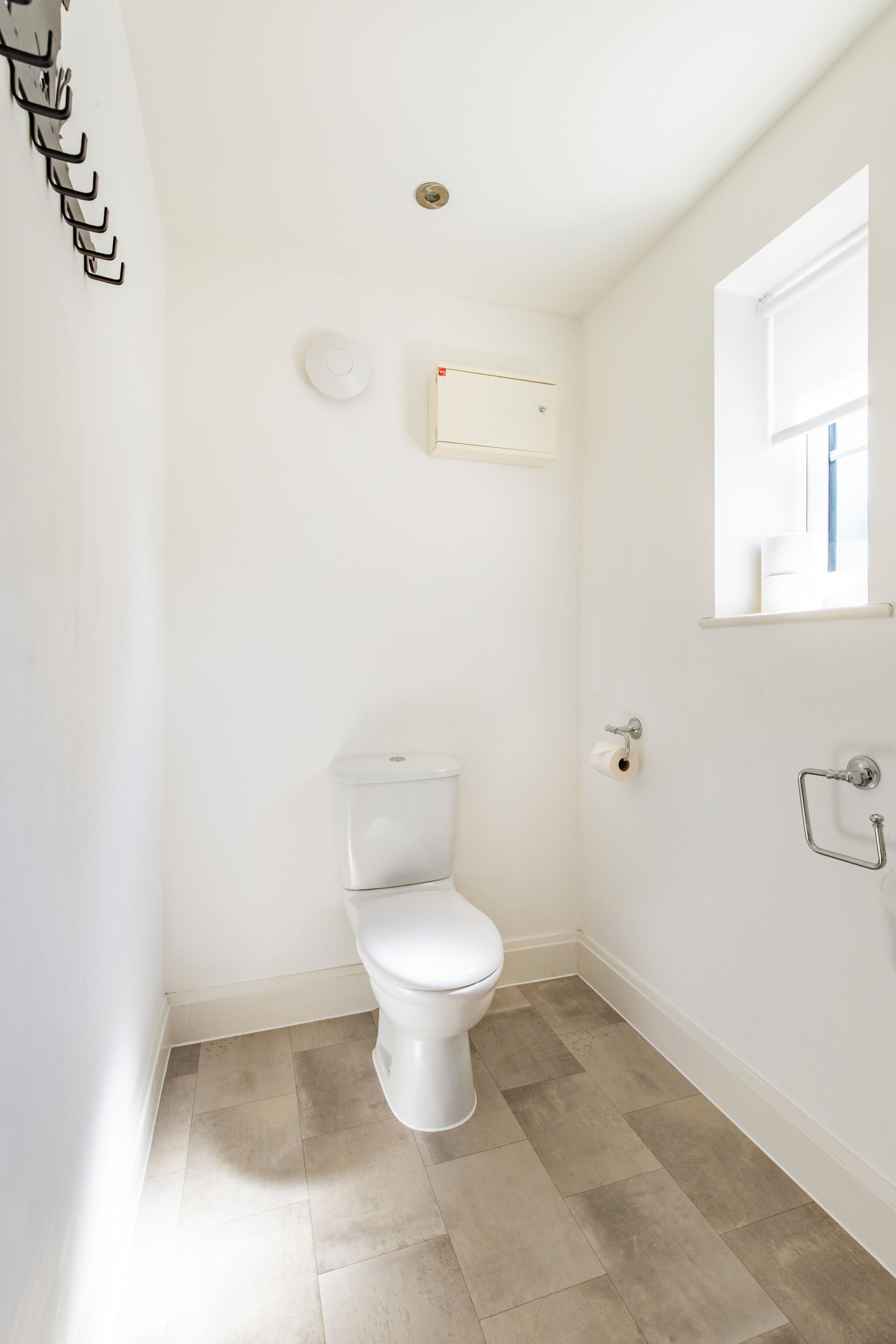 A small, clean bathroom with a toilet, a towel rack, and a mirror.