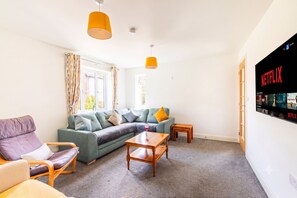 A living room with a sectional sofa, a wooden coffee table, and a TV mounted on the wall displaying the Netflix logo. - A slow Norfolk weekend in a village near Norwich (Norwich)