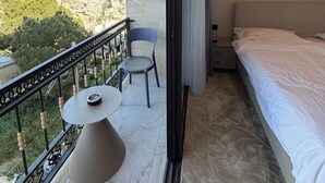 Varanda com mesa, cadeiras, uma cama e vista para a paisagem urbana.