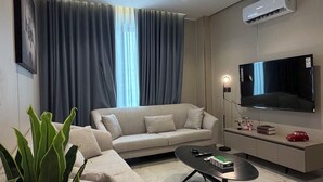 Uma sala de estar moderna com sofá, mesa de centro, TV e aparelho de ar condicionado.